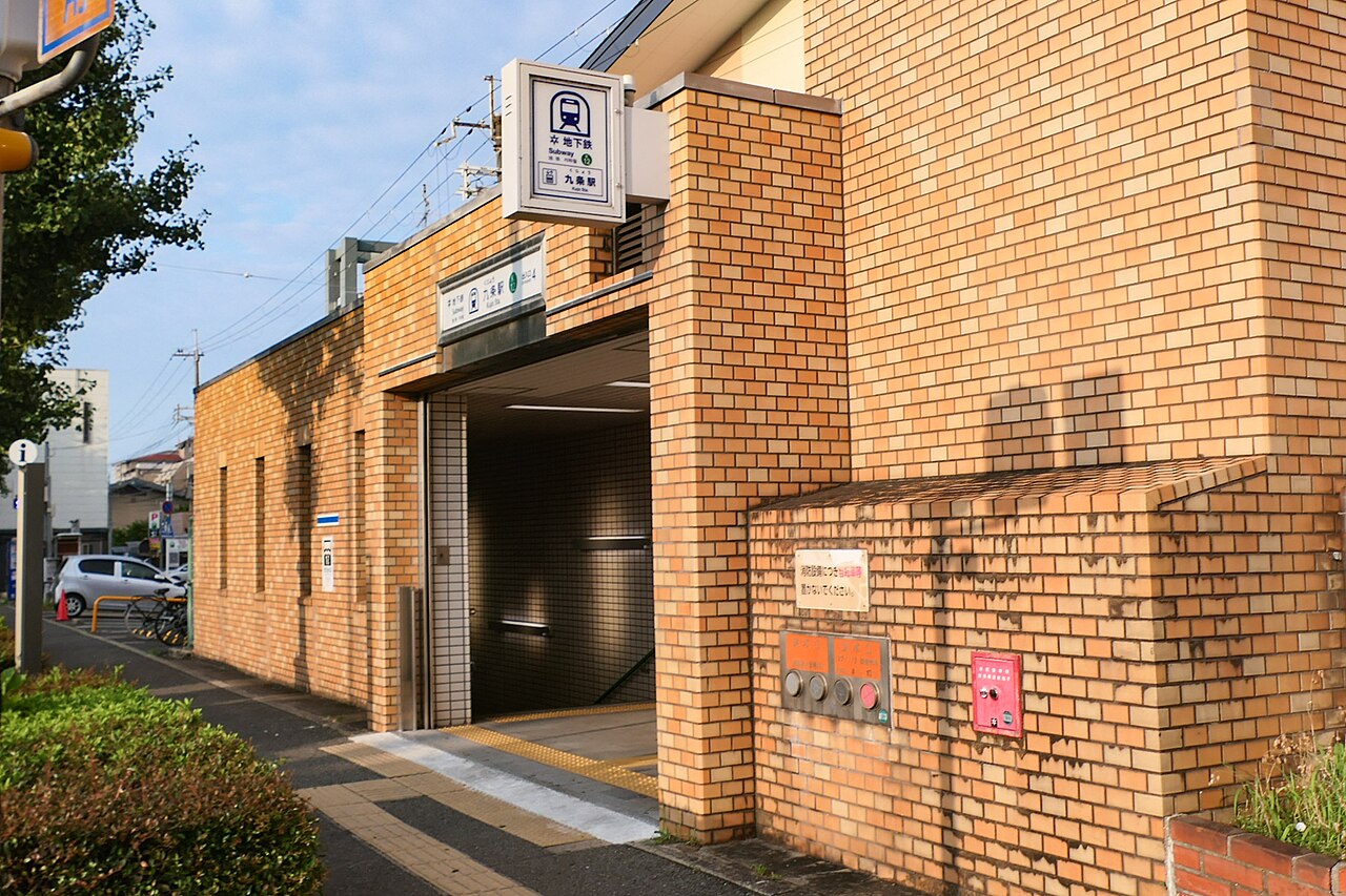 九条駅 표지가 걸린 주황색 벽돌 외벽의 구죠역 지상 출입구와 아래로 이어지는 계단
